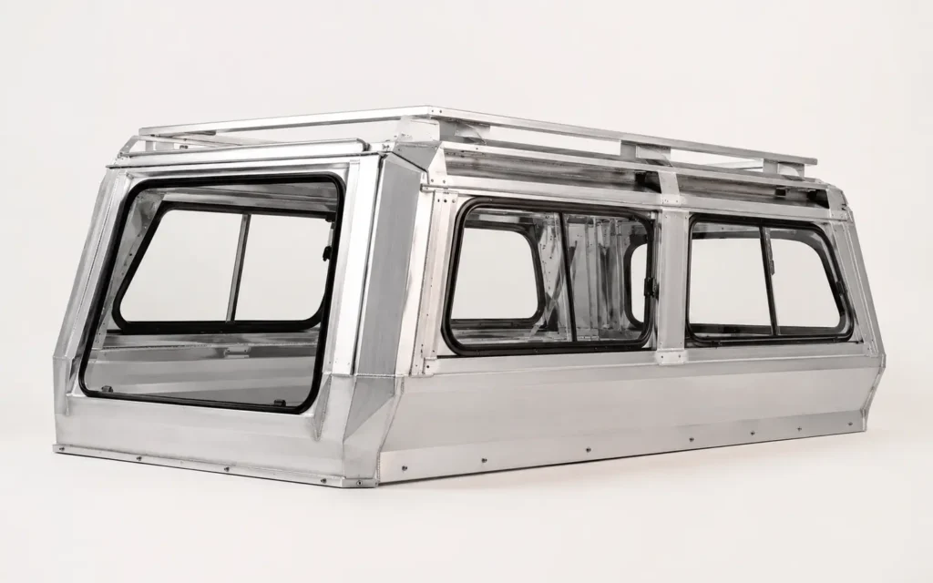 Raw aluminum pickup truck canopy showing precision folded panels and structural frame
