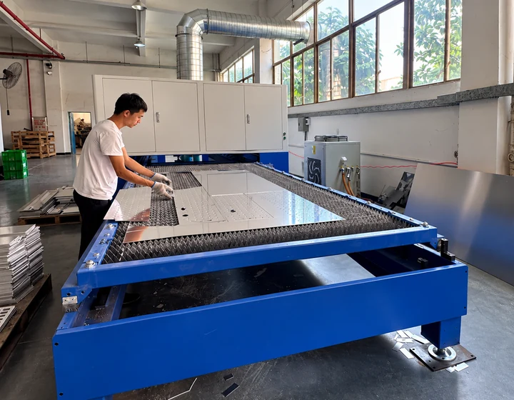 Worker preparing aluminum canopy panels on a laser cutting table
