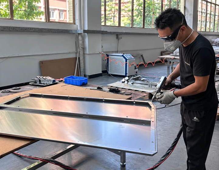 Worker joining an aluminum truck canopy panel at the welding bench