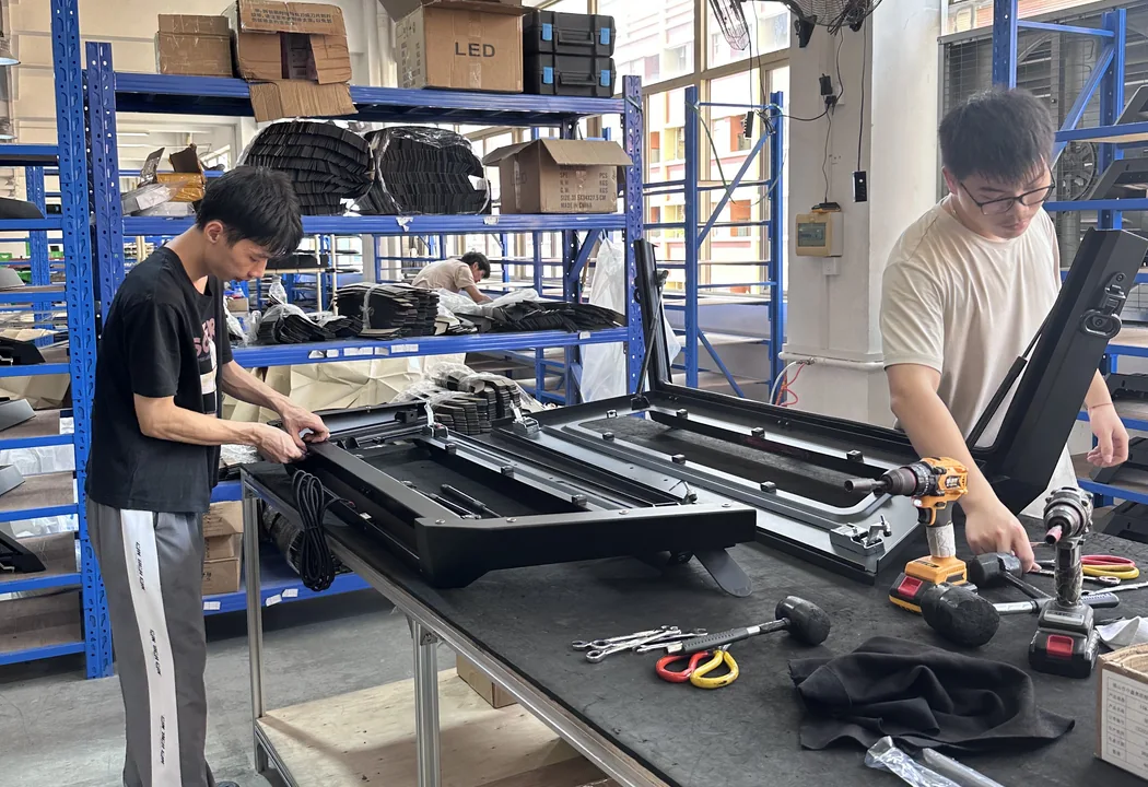 Technicians working on a canopy assembly at a workshop bench